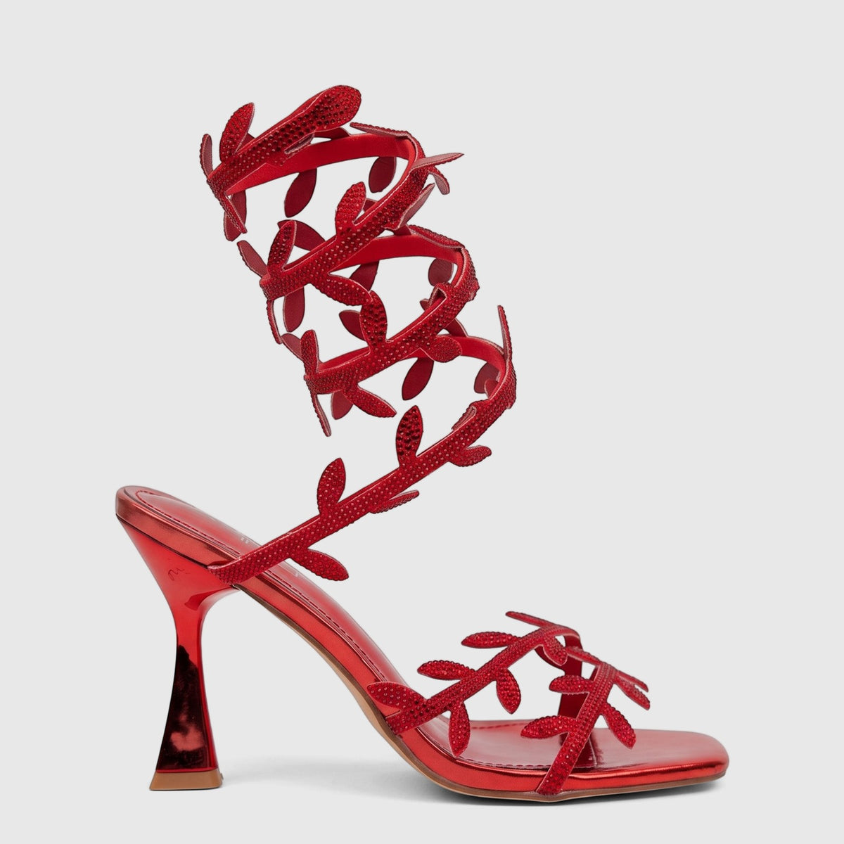A striking red Bulbul Ladies Spiral Strap Evening Heel Sandal with a metallic finish and rhinestone leaf embellishments.