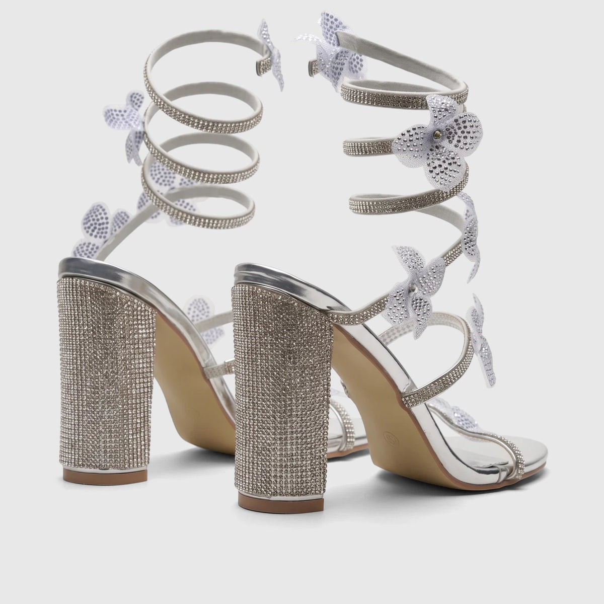 Pair of silver Bulbul Ladies Spiral Strap Evening Heel Sandals, adorned with glittering rhinestones and elegant spiral ankle