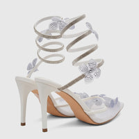 A pair of white Bulbul Ladies Spiral Strap Evening Heel Sandals with sparkling rhinestone details and silver flower