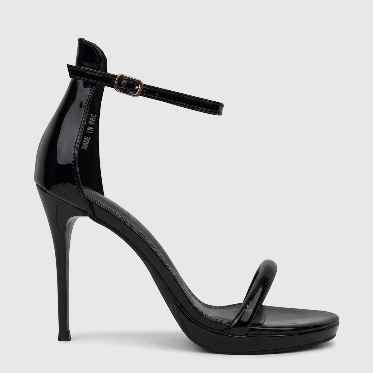 Bulbul Ladies Stiletto Heel Sandal in black patent leather with clear PVC straps and an ankle buckle, shown from the side.