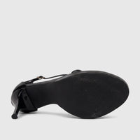 Underside view of a black patent leather Bulbul ladies stiletto heel sandal, showcasing the textured sole and slender heel.