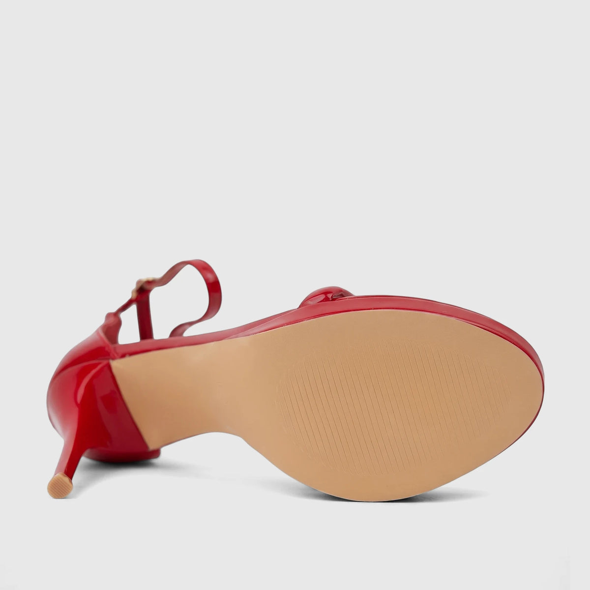 Red patent stiletto heel sandal for ladies, shown from a bottom-side view with a textured beige sole and ankle strap.