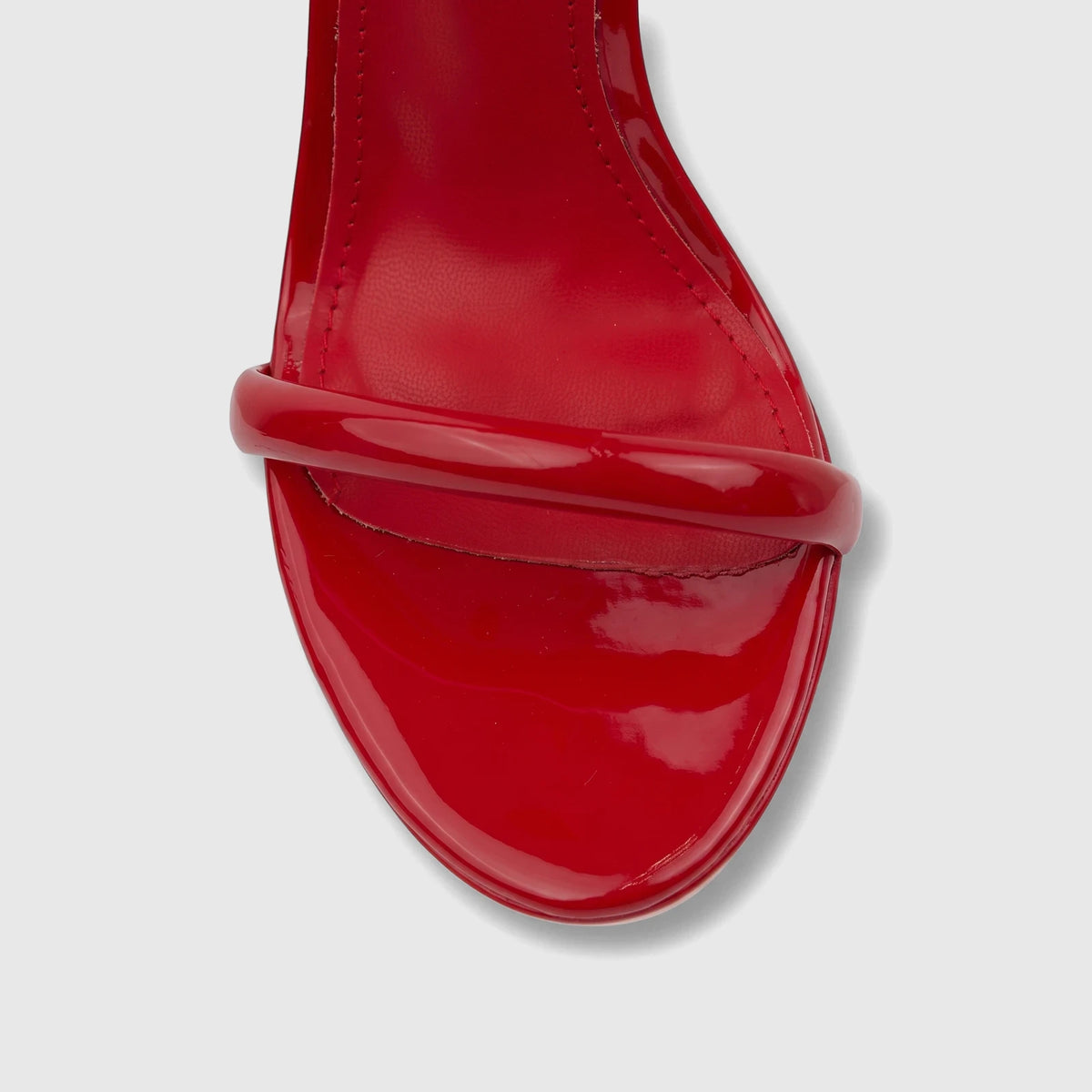 Close-up of a vibrant red patent leather Bulbul Ladies Stiletto Heel Sandal, showcasing the toe strap and glossy finish.