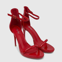 Pair of Bulbul Ladies Stiletto Heel Sandals in vibrant red patent leather, featuring clear ankle and toe straps, displayed