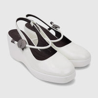A pair of white patent leather Bulbul Ladies Dress Block Heel Sandals with slingback straps and black insoles, showcased