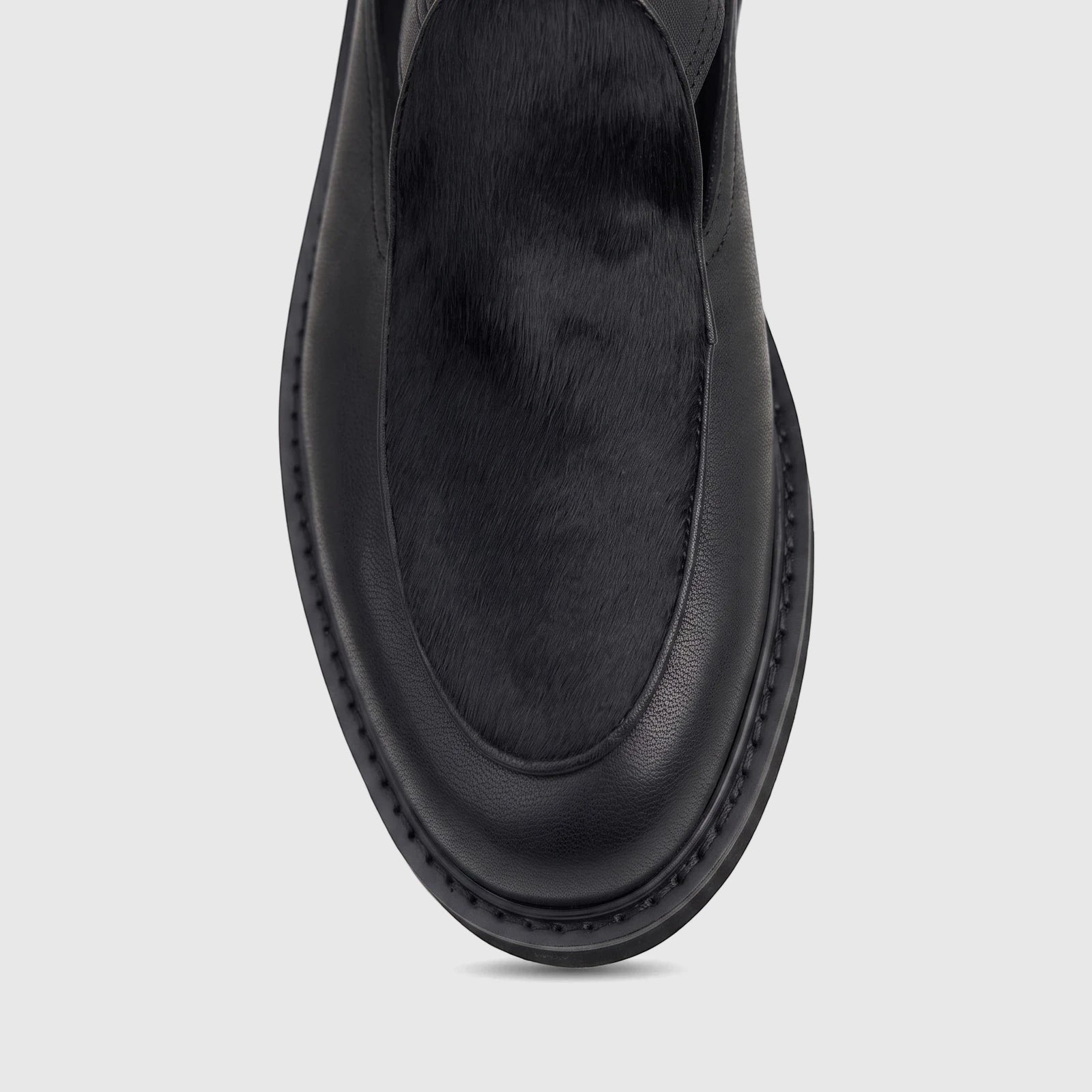 Black men's leather chunky sole sandal with a fur panel, featuring prominent sole stitching, viewed from above.