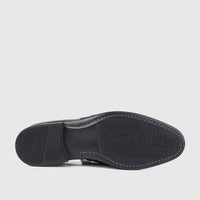 Bottom view of a Bulletti men's black leather dress slip-on shoe, showcasing the textured rubber sole with white stitching.