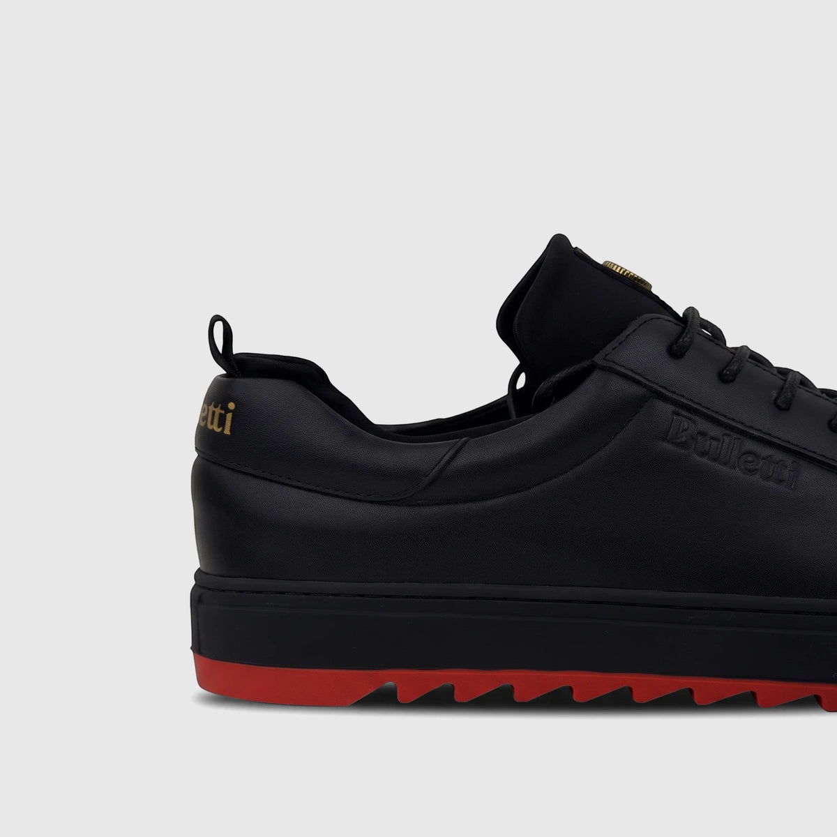 Bulletti Men's black leather sneaker with a red jagged sole, shown from a side view on a white background.