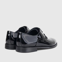Two shiny black patent leather men's dress shoes with laces, viewed from the back-right on a a white background.