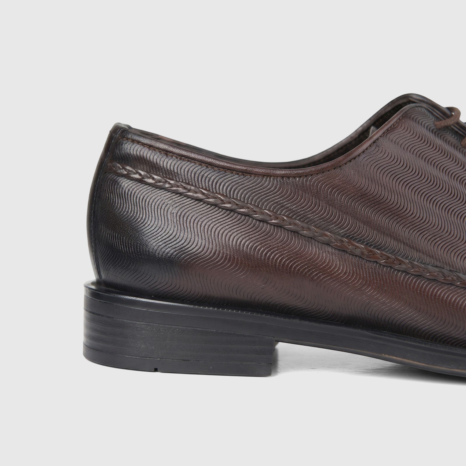 Side view of a Bulletti Men's Brown Leather Dress Lace Up Shoe featuring a distinctive wavy pattern and braided leather