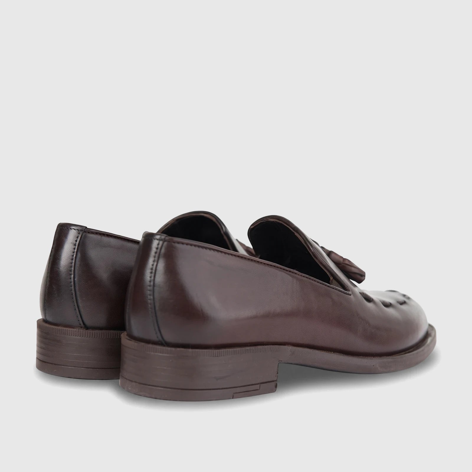 Pair of men's Bulletti brown leather dress slip-on shoes with decorative tassels, viewed from a rear-side angle.