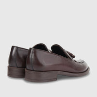 Pair of men's Bulletti brown leather dress slip-on shoes with decorative tassels, viewed from a rear-side angle.