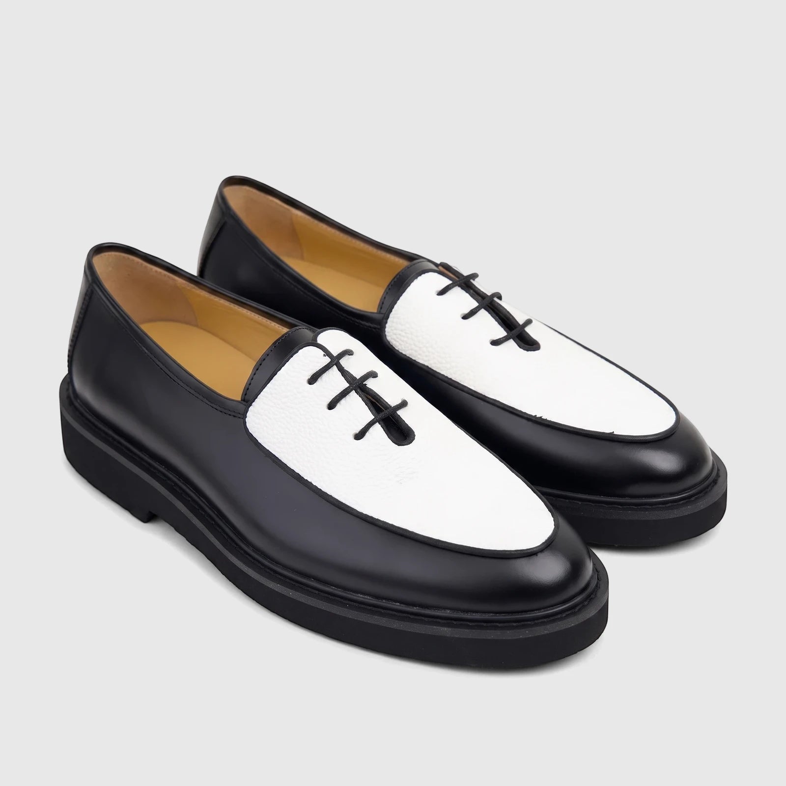 A pair of Bulletti men's leather chunky sole lace-up shoes in a distinctive black and white design, presented from a high