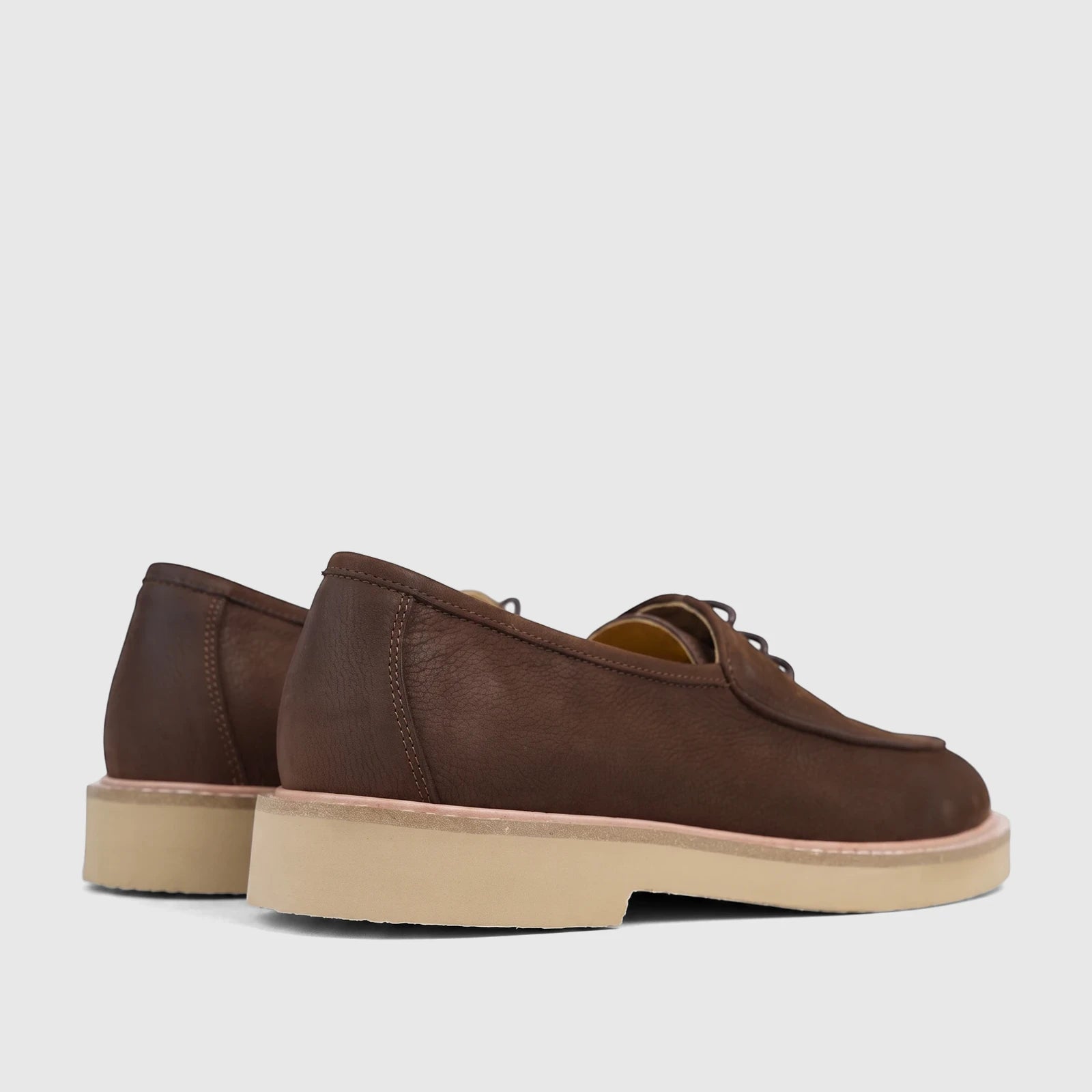 Brown leather men's lace-up shoes with chunky soles, shown from a side and rear view on a white surface.