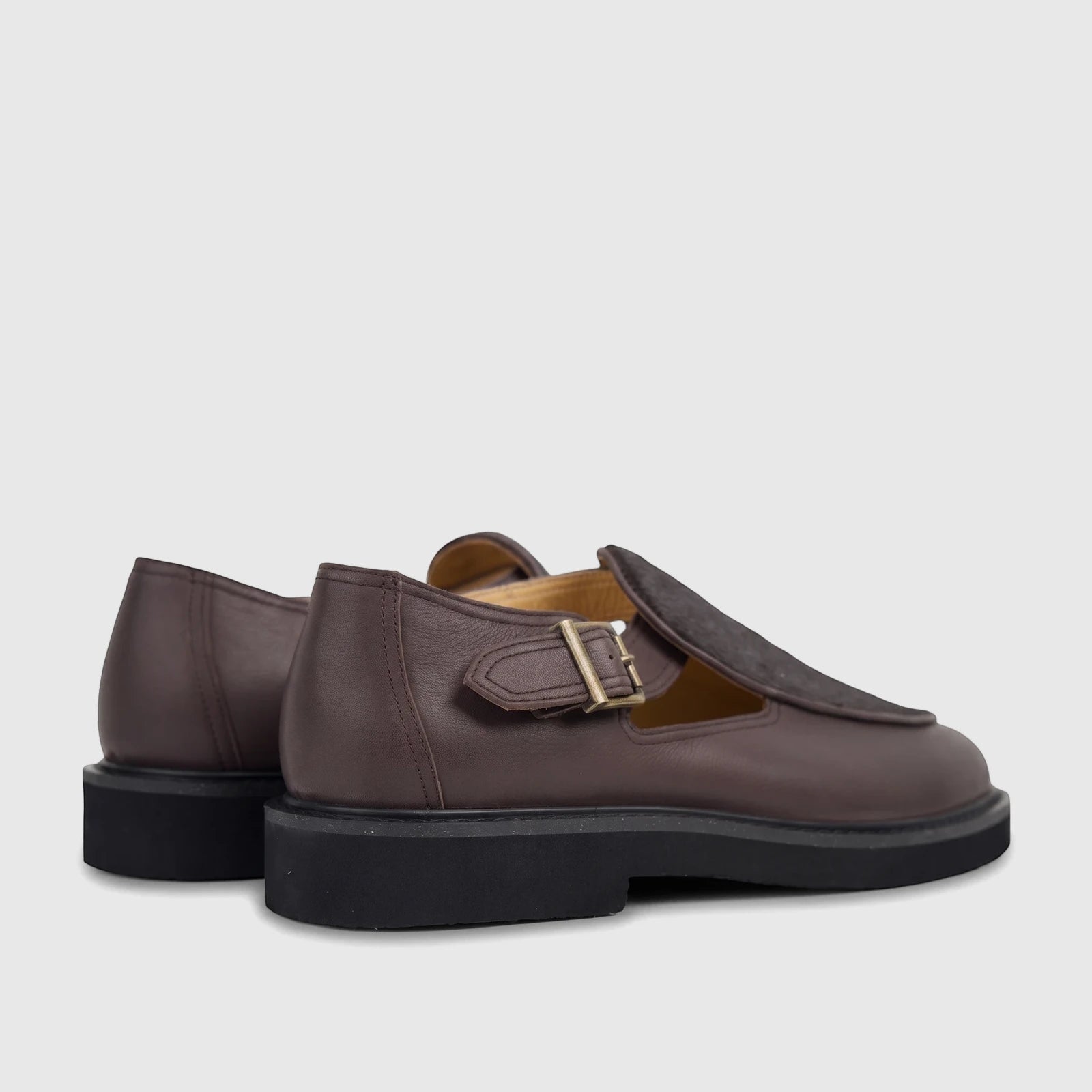 A pair of Bulletti Men's Leather Chunky Sole Sandal in stallion brown, featuring a brass buckle and thick black sole, viewed