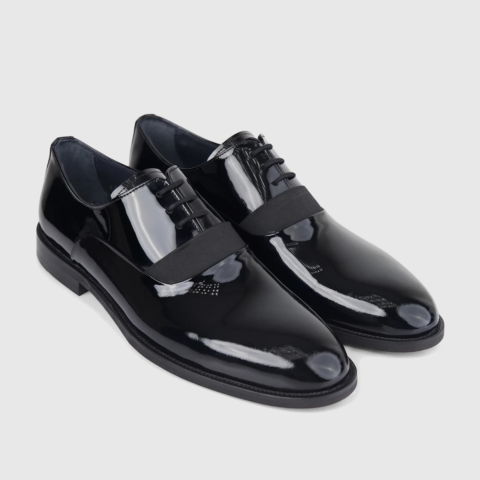 A pair of glossy black Bulletti Men's Leather Dress Lace Up 128-21 Black Patent shoes, angled to show the sleek design and
