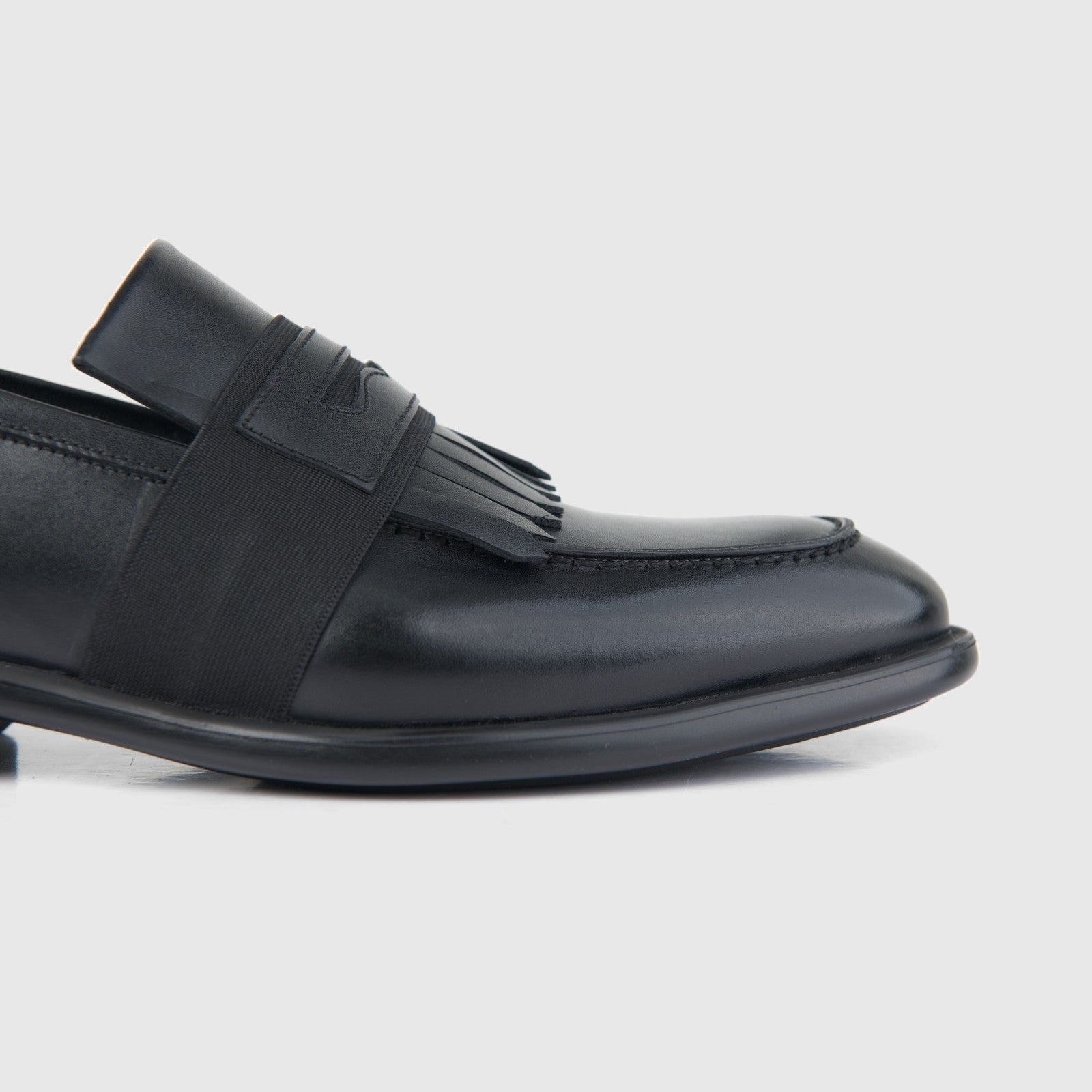 Bulletti men's leather dress slip-on with fringe 4-162 in black, close-up side view showing elastic band and toe.