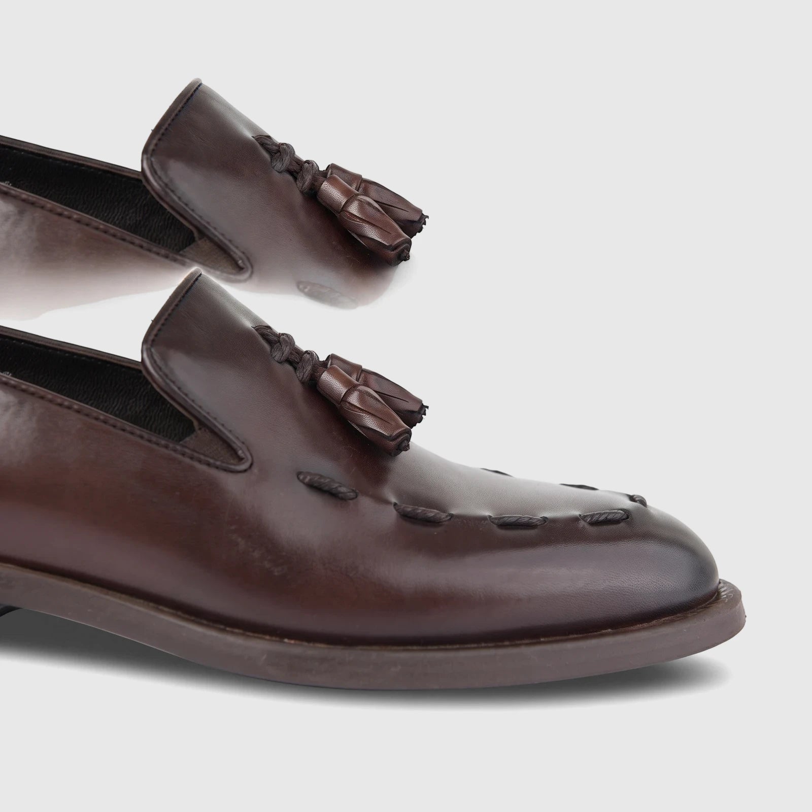 Bulletti Men's Leather Dress Slip On shoe in dark brown, featuring decorative tassels and moc-toe stitching, shown from a
