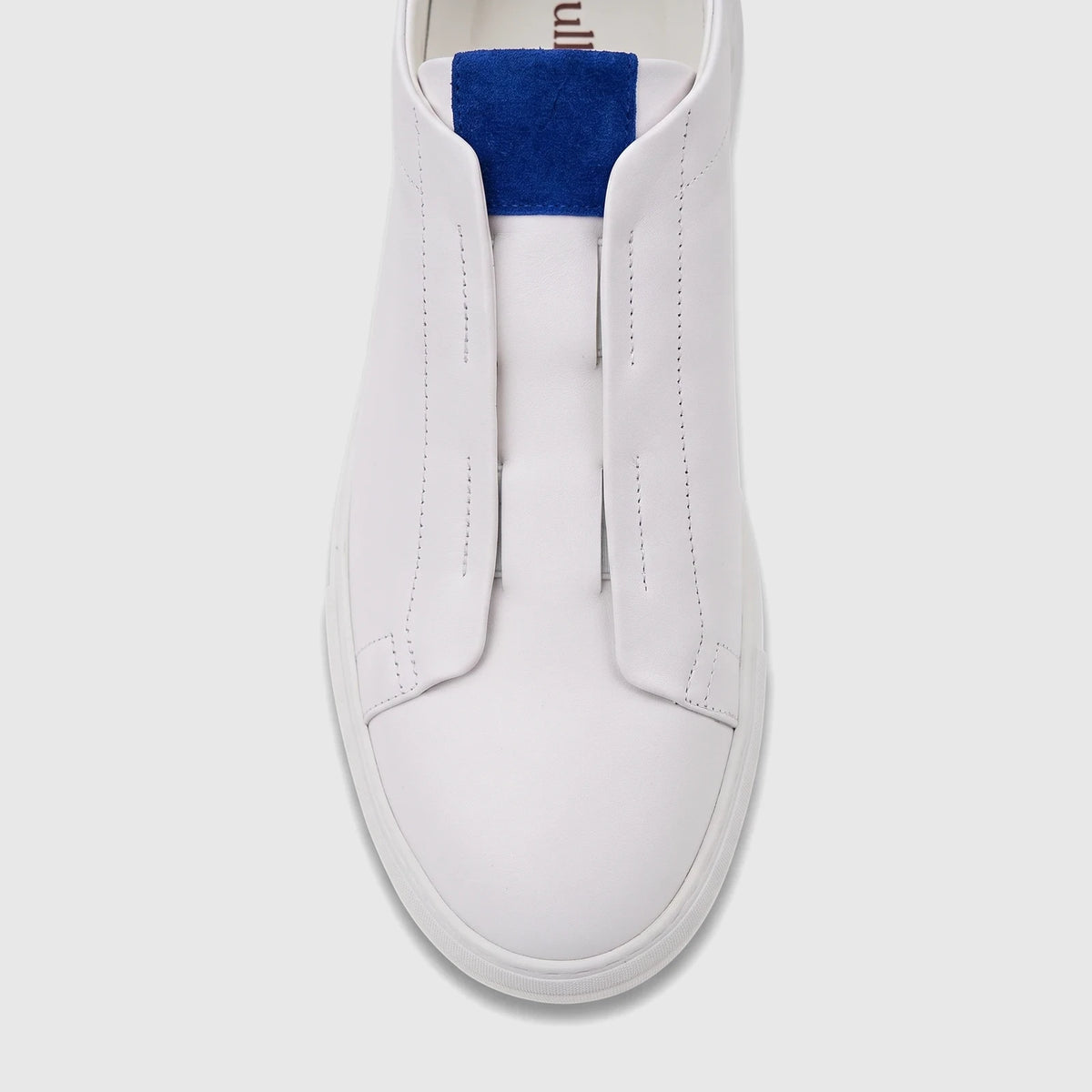 Top-down view of a Bulletti Men's Leather Sneaker. White slip-on design with a blue accent, featuring smooth leather and