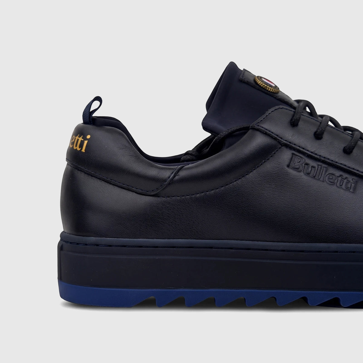 Close-up of a Bulletti Men's Leather Sneaker in dark blue, showcasing its textured leather and layered sole from a side