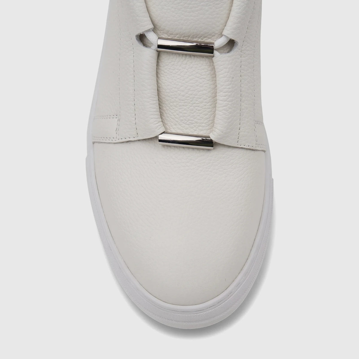 Close-up of a white Bulletti men's leather sneaker with silver metallic hardware detail on the vamp.
