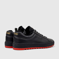 Pair of Bulletti Men's Leather Sneakers in black, featuring distinctive red serrated soles, viewed from a side-rear angle.