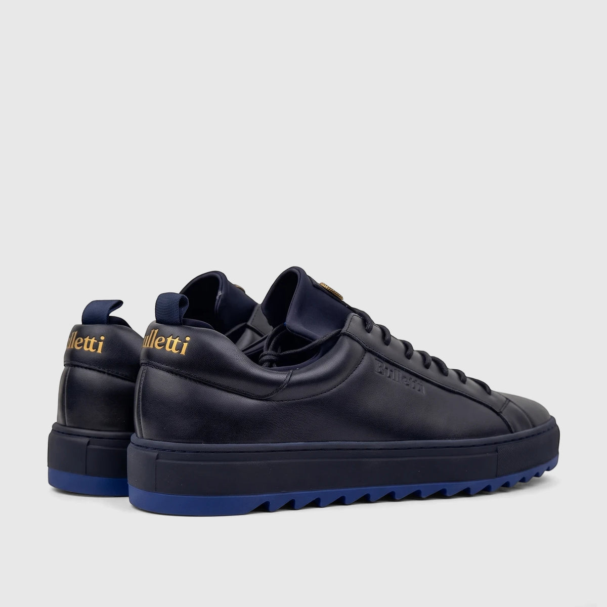 Dark blue Bulletti men's leather sneakers, model HASM-001, with royal blue soles and gold heel logos, shown from a rear-side