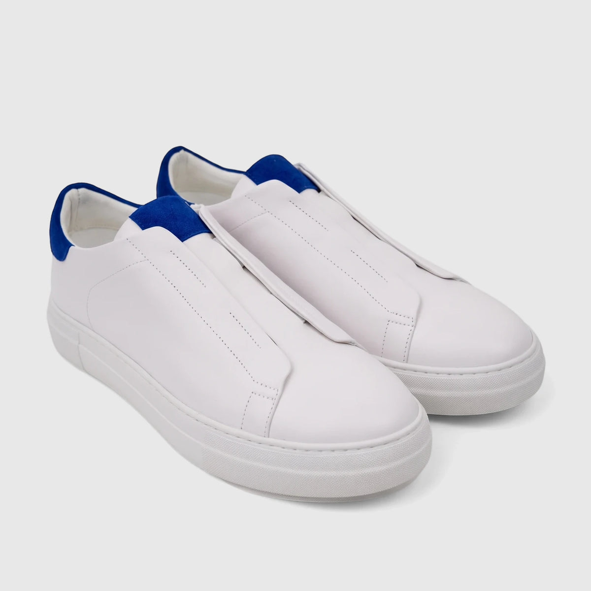 Pair of Bulletti Men's Leather Sneakers in white with blue heel accents, featuring a slip-on design and white rubber soles.