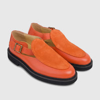 A pair of Bulletti Unisex chunky sole sandals in vibrant majesty orange leather with suede accents and brass buckles, seen