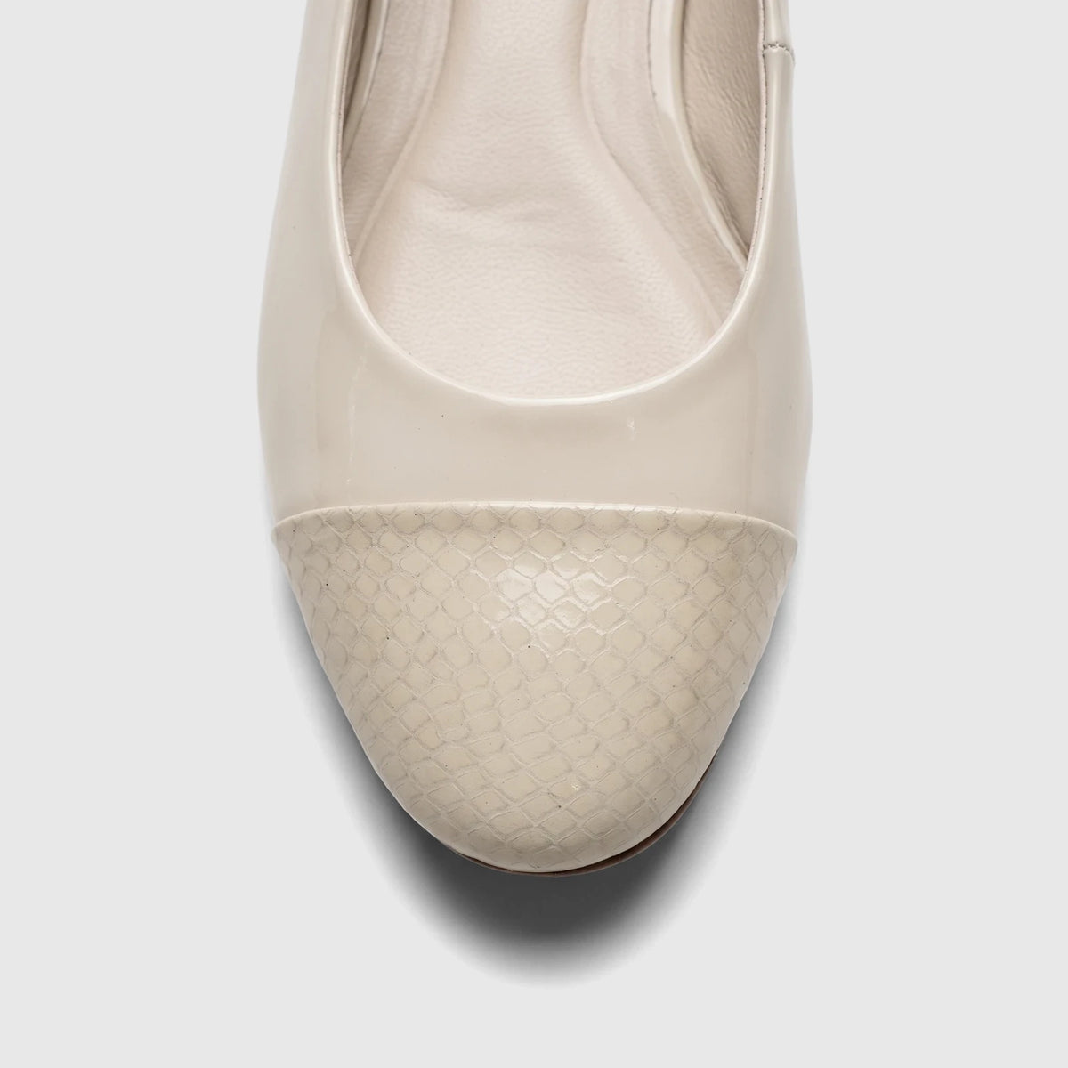 Close-up front view of a bone Capelli Rossi ladies' flat shoe featuring a shiny patent leather upper and a textured