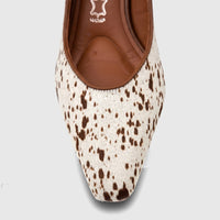 Close-up of a Capelli Rossi leather block heel court shoe in white and brown cow print, featuring a pointed toe.
