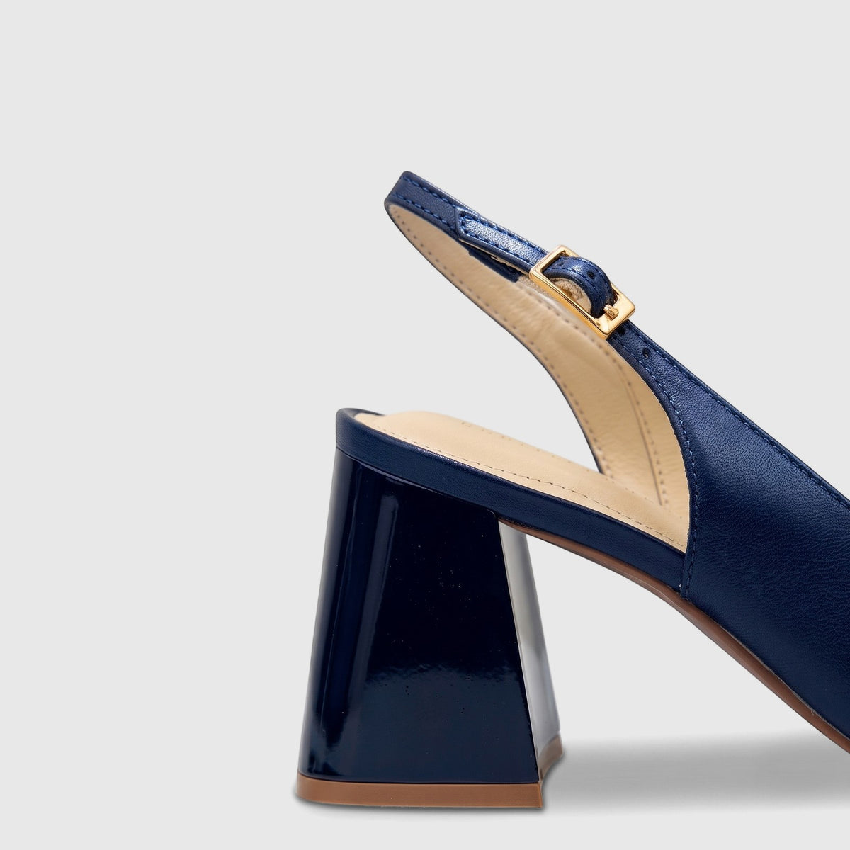 Deep blue leather ladies slingback court shoe with a block heel and gold buckle closure, partial view.