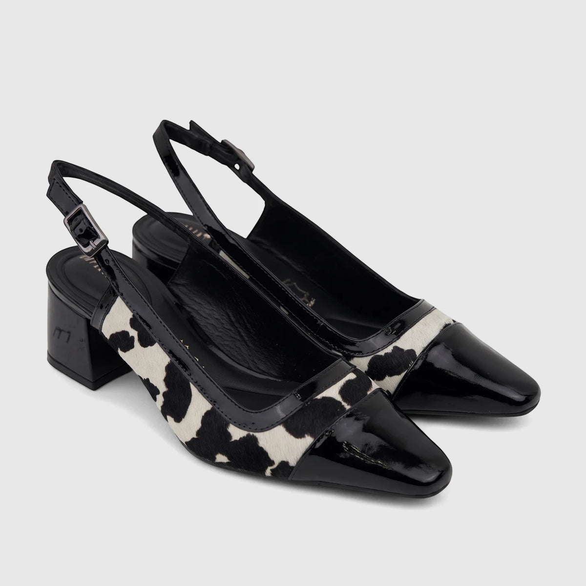 Two black and white cow print Capelli Rossi slingback block heel court shoes made of leather and cow hair.