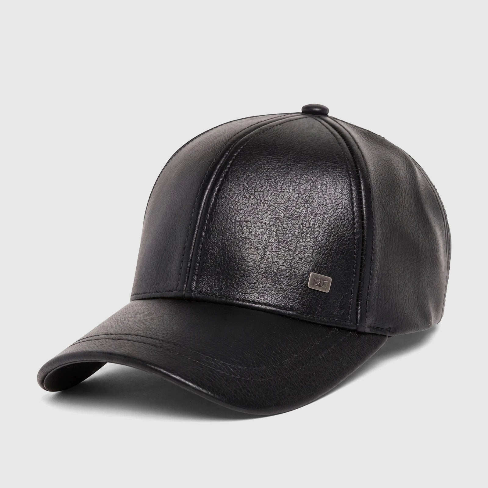 Close-up of a pitch black faux leather Cat Heritage baseball cap, featuring a curved brim and a metal logo tag.