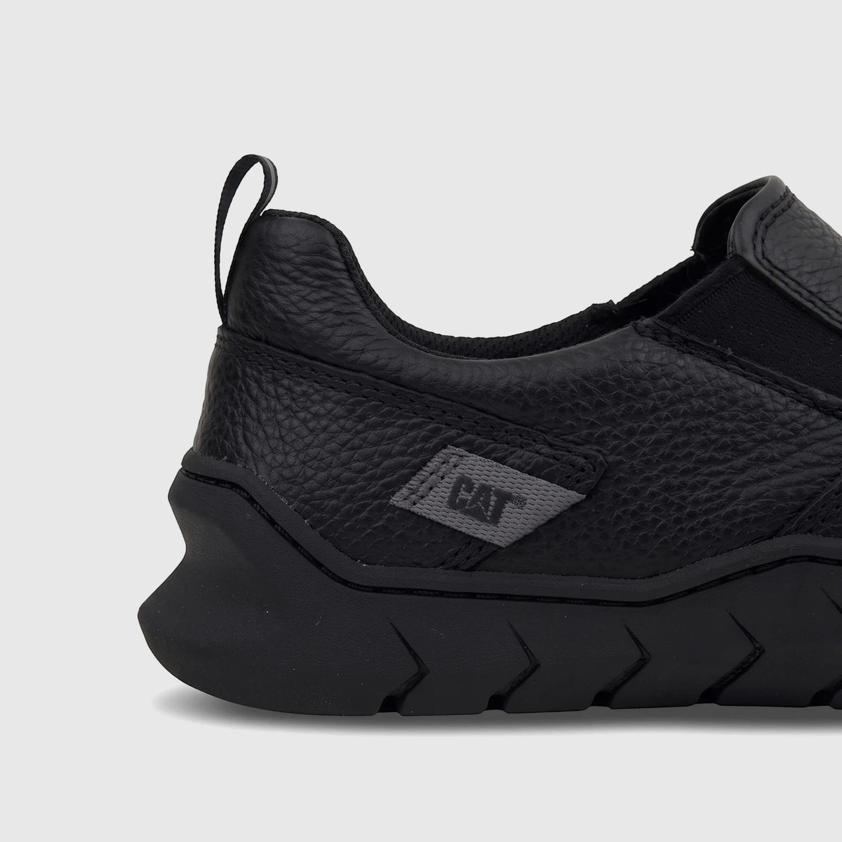 Close-up side view of a black Cat Men's Flexion Slip On shoe, made of textured leather with a distinctive pattern on the