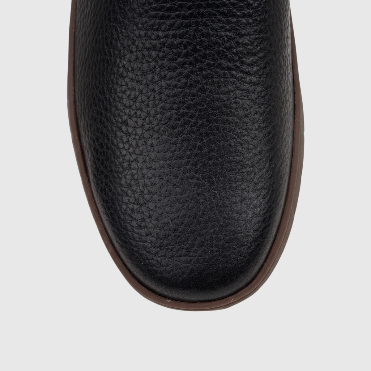 Close-up top view of a black pebbled leather Cat Men's Flexion Slip On shoe with a contrasting brown sole.