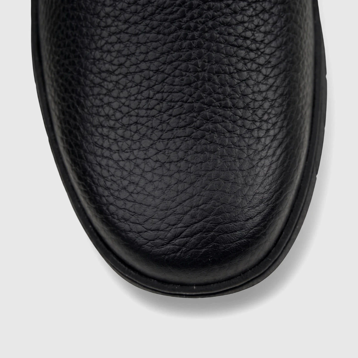 Close-up overhead view of the toe area of a black Cat Men's Flexion slip-on shoe, featuring textured leather.