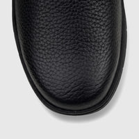 Close-up overhead view of the toe area of a black Cat Men's Flexion slip-on shoe, featuring textured leather.