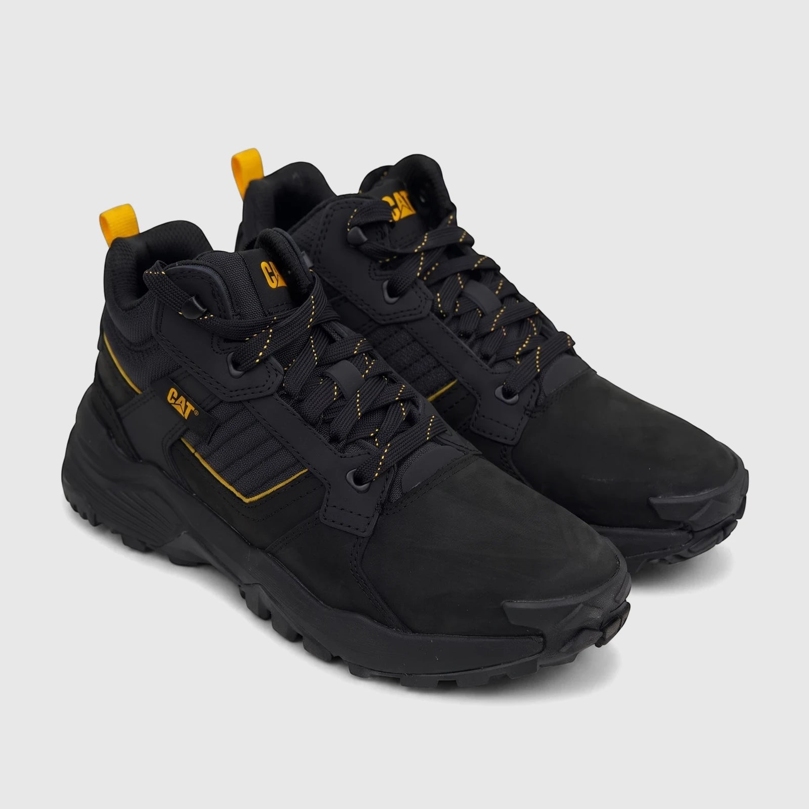 Pair of black Cat Men's Grapple Leather Mid P726961 work boots with yellow laces and accents, angled view.