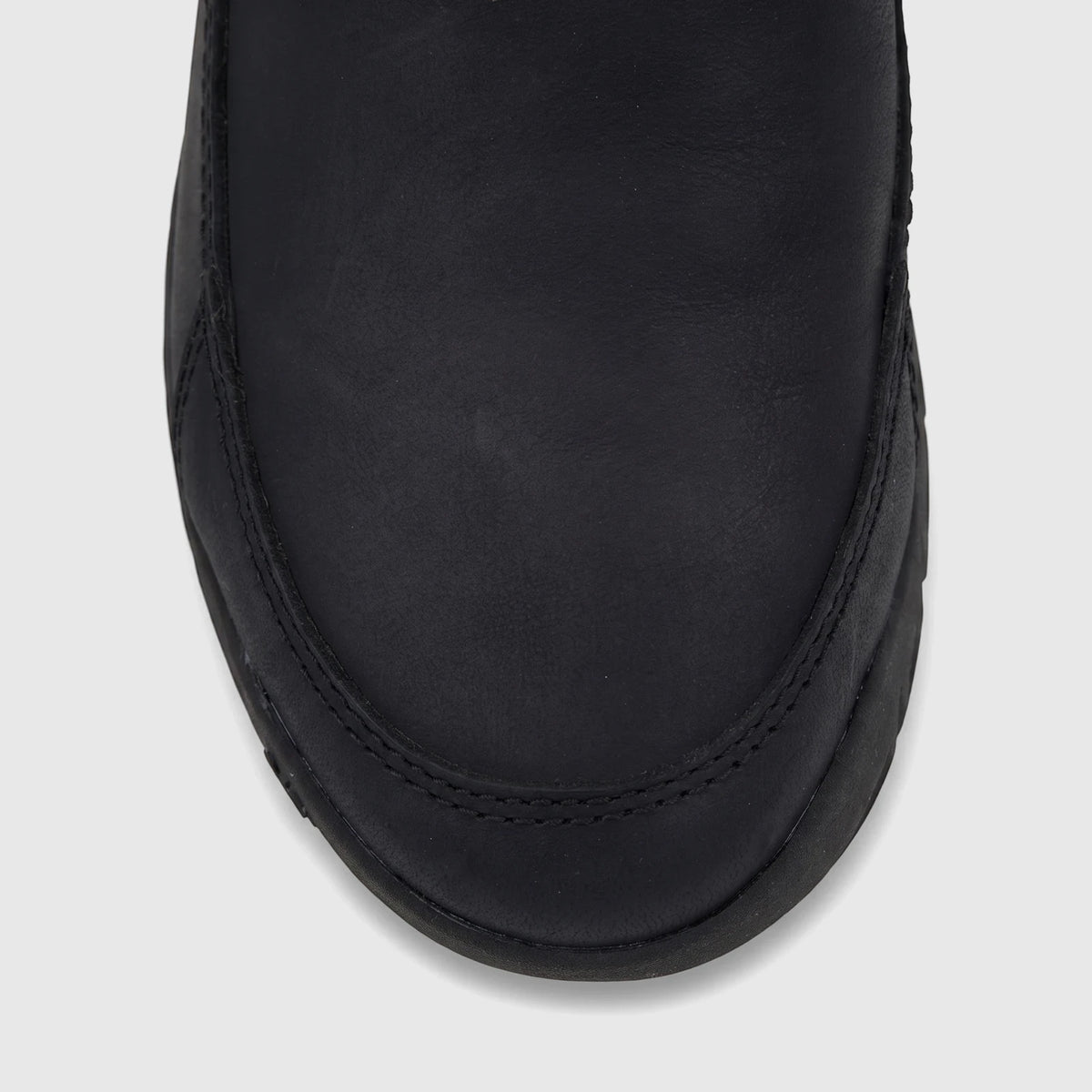 Cat Men's Versage slip-on shoe in black leather, shown in a close-up overhead view focusing on the toe box and vamp.