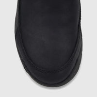 Cat Men's Versage slip-on shoe in black leather, shown in a close-up overhead view focusing on the toe box and vamp.
