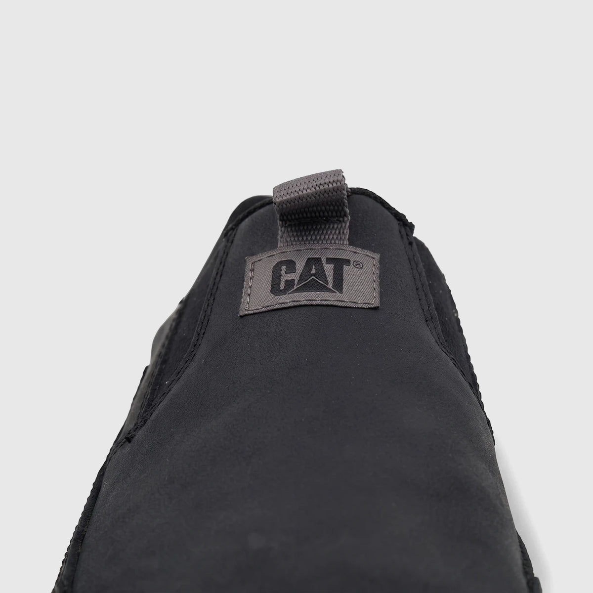 Close-up of a single black Cat Men's Versage slip-on shoe, featuring the grey brand logo on the tongue.