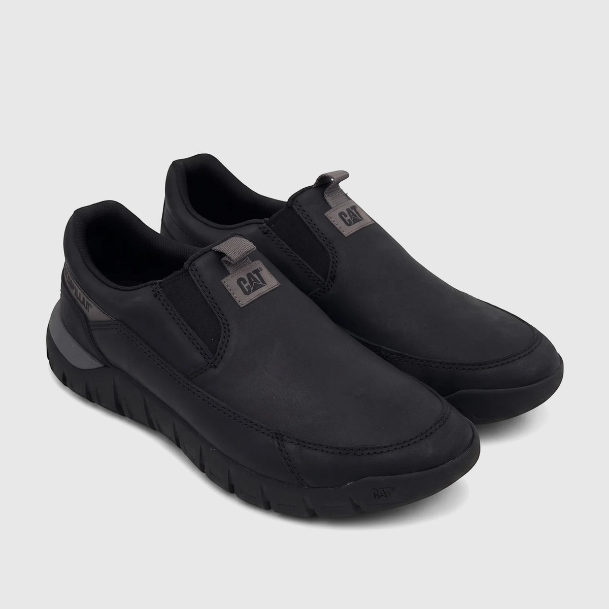 A pair of black Cat Men's Versage slip-on shoes with a matte leather-like finish and gray logo labels, viewed from an angled