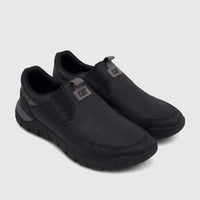A pair of black Cat Men's Versage slip-on shoes with a matte leather-like finish and gray logo labels, viewed from an angled