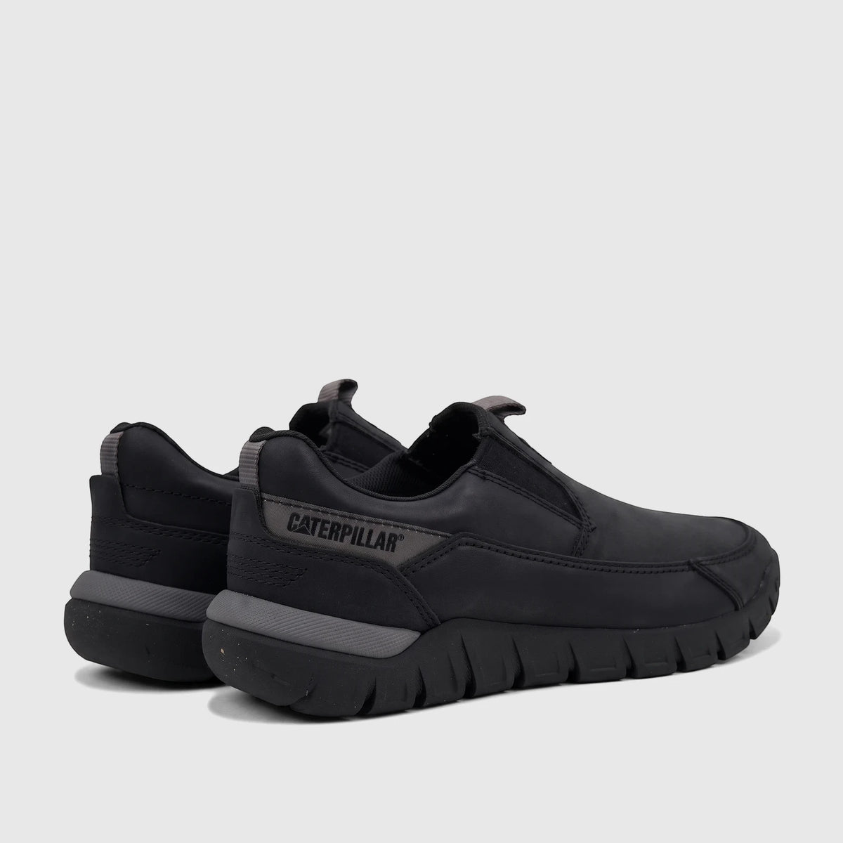 A pair of black Cat Men's Versage slip-on shoes, seen from a side angle, featuring grey trim and a durable sole.