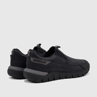 A pair of black Cat Men's Versage slip-on shoes, seen from a side angle, featuring grey trim and a durable sole.