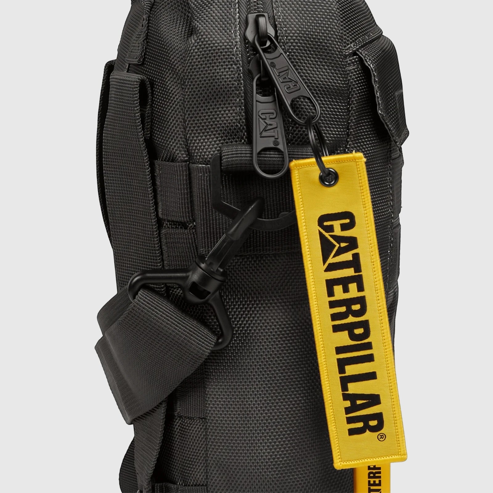 Close-up of a black textured Cat Namib Tablet Bag with zippers featuring the 'CAT' logo and a prominent yellow 'CATERPILLAR'