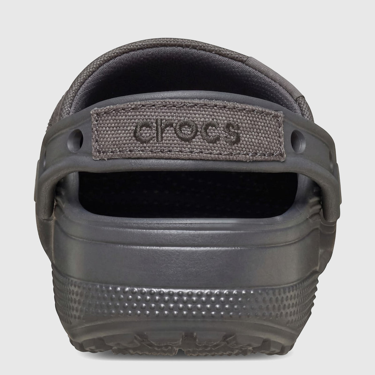 Back view of a Classic Crafted Clog in Black Sand, featuring a textured sole and a fabric heel strap with Crocs branding.