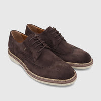 A pair of men's Crockett and Jones brown suede lace-up brogues with wingtip detailing and white soles, angled on a white