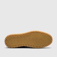 Underside view of a Crockett and Jones men's casual shoe, featuring a chunky brown rubber sole with prominent ridged